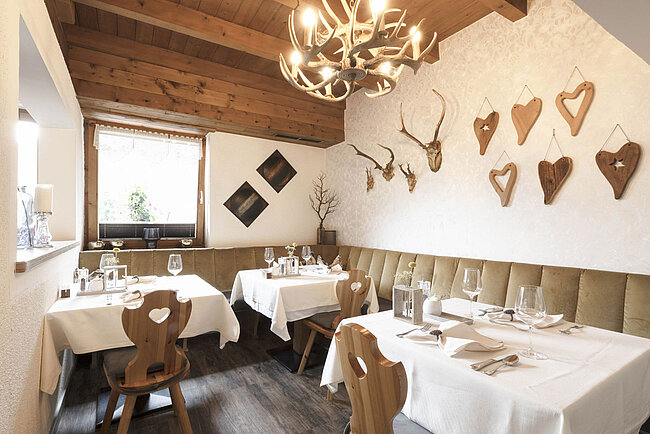 Gemütliche Stube zum Essen und Trinken im Tiroler Stil mit Holz und mit liebevoller Dekoration an den Wänden.