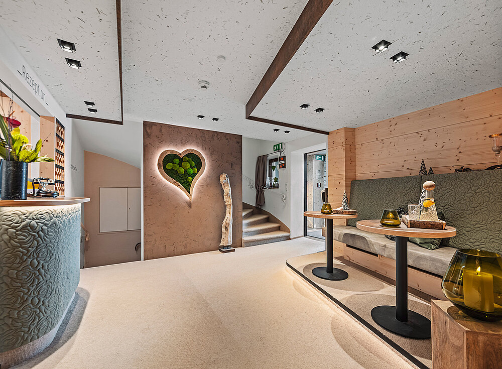 Moderner Loungebereich mit herzförmiger Wanddekoration, gemütlichen Sitzgelegenheiten, kleinen Tischen und sanfter, warmer Beleuchtung.