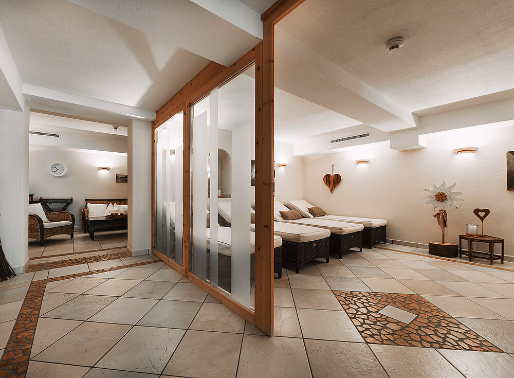 Ein moderner Spa-Entspannungsraum mit Liegestühlen, gefliesten Böden, sanfter Beleuchtung und dekorativer Wandkunst.