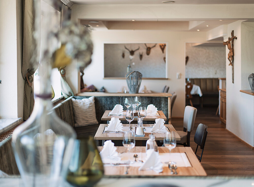 Ein gemütlicher, eleganter Restaurant-Essbereich mit gedeckten Tischen, Holzböden und sanftem Tageslicht.