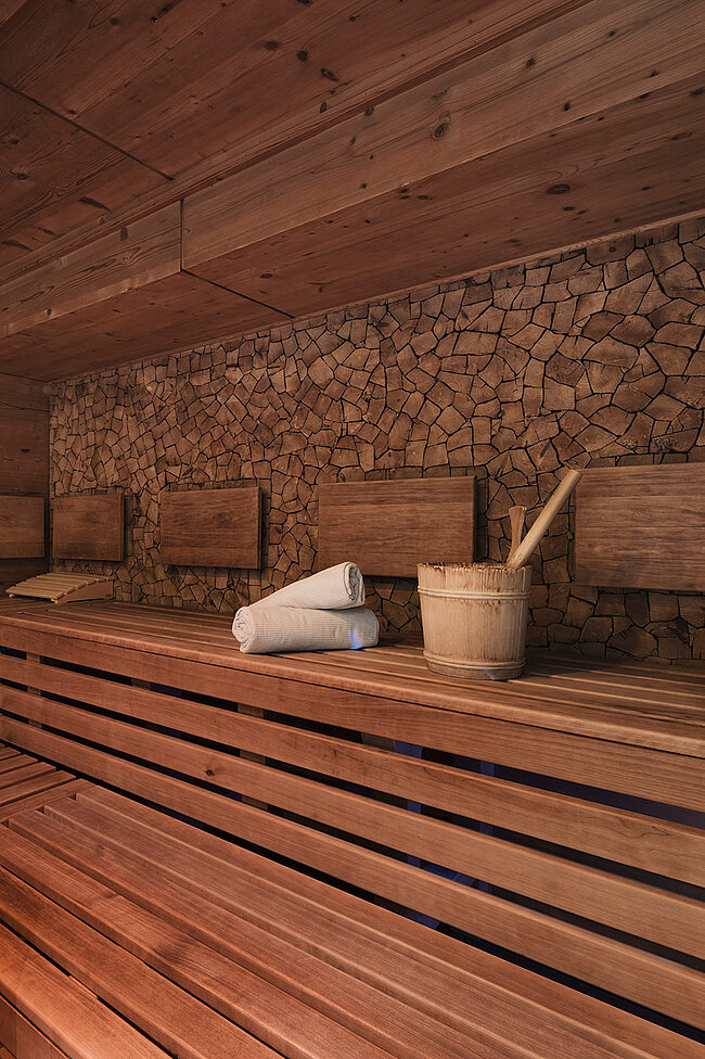 Saunaeinrichtung aus Holz mit Bänken, Handtüchern und Eimer im Bergblick, einem Hotel in Neustift, Stubaital.