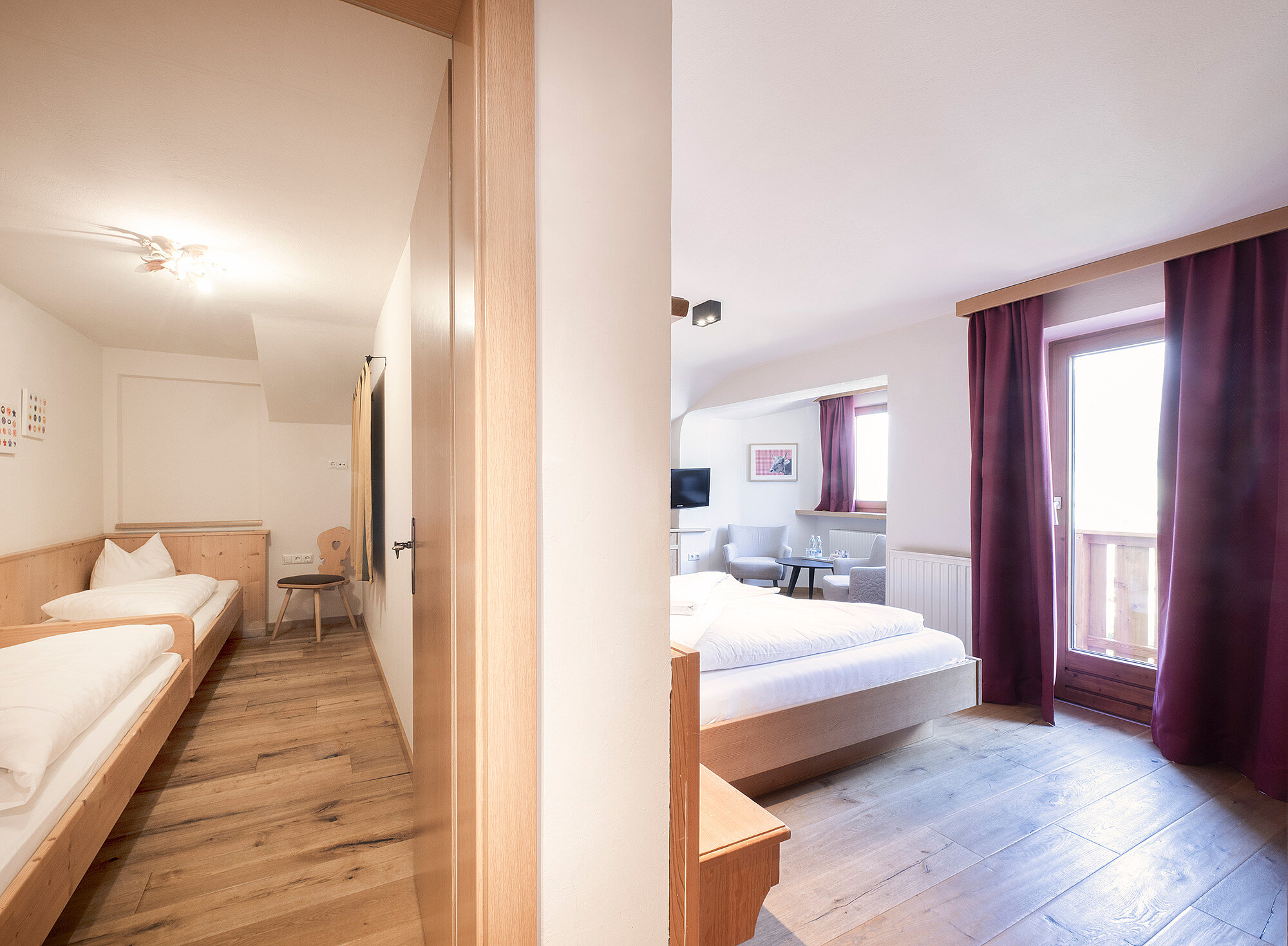 Eine helle Hotelsuite verfügt über ein Einzelbett und ein Doppelbett in separaten Zimmern, die durch eine Teilwand voneinander getrennt sind.