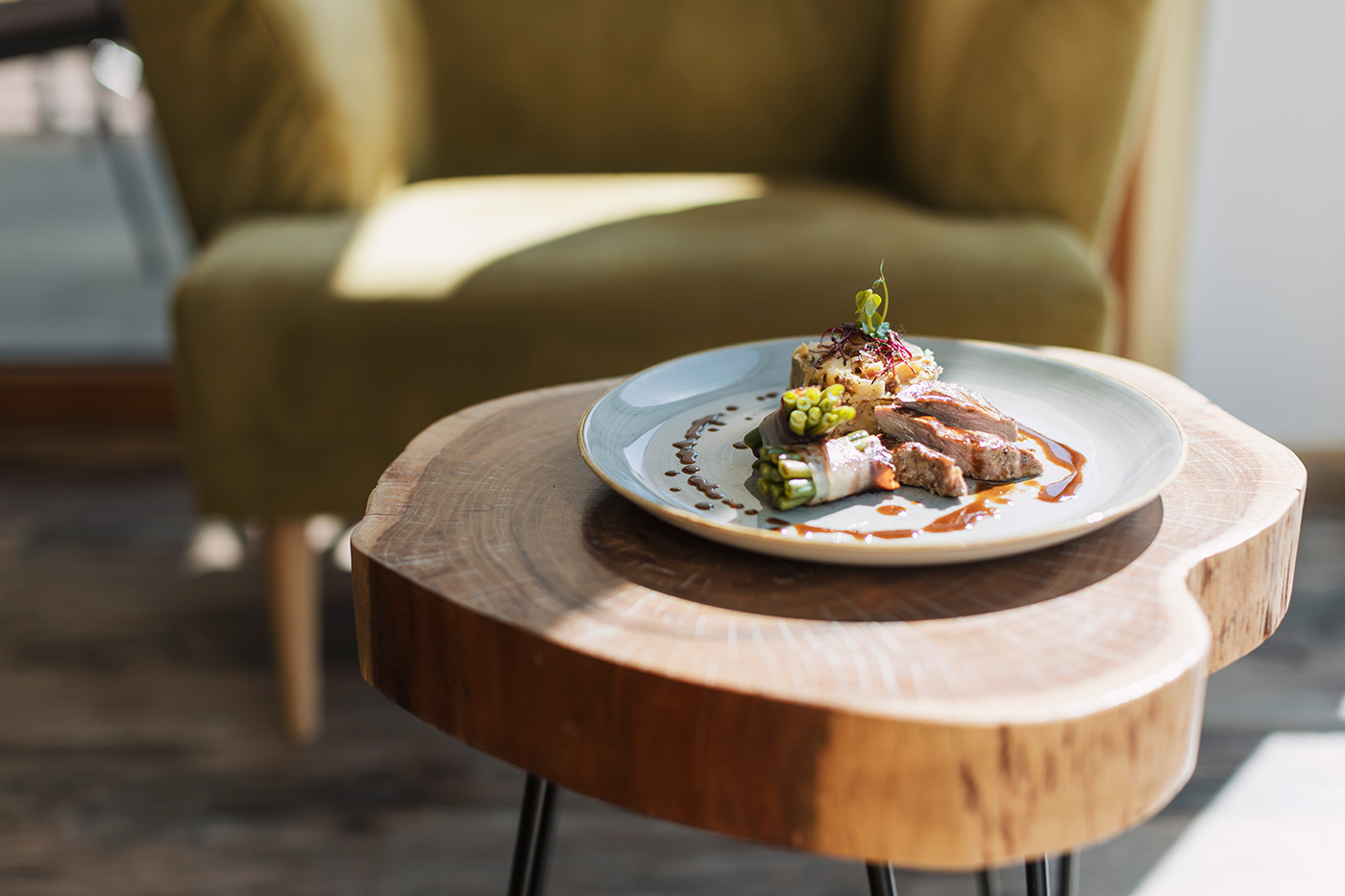 Ein Gourmet-Menü auf einem weißen Teller steht auf einem rustikalen Tisch im Hotel Neustift im sonnendurchfluteten Stubaital.